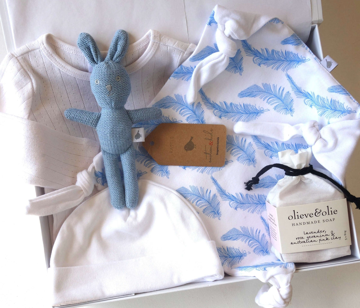 Welcome little one gift hamper featuring baby clothes, a soft toy, and handmade soap for new parents.