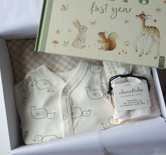 Unisex baby gift hamper featuring a record book, baby clothes, and handmade soap in a beautifully arranged box.