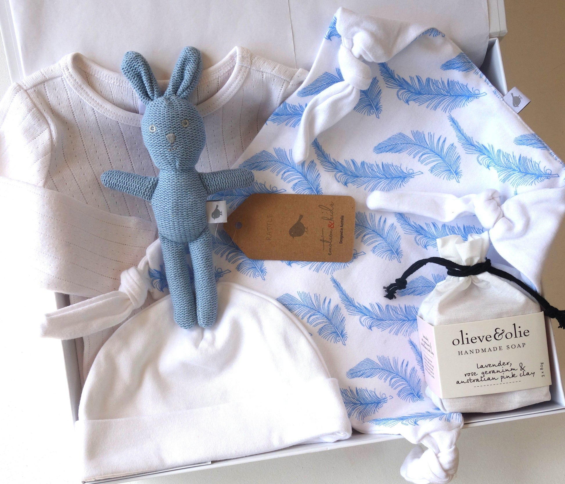Welcome little one gift hamper featuring baby clothes, a soft toy, and handmade soap for new parents.