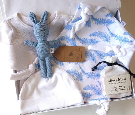 Welcome little one gift hamper featuring baby clothes, a soft toy, and handmade soap for new parents.
