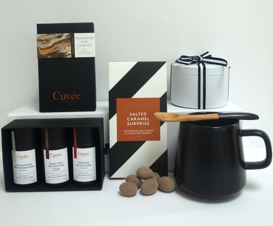 Chocolate lovers gift box featuring artisan chocolates, hot chocolate trio, and a black mug with bamboo spoon.