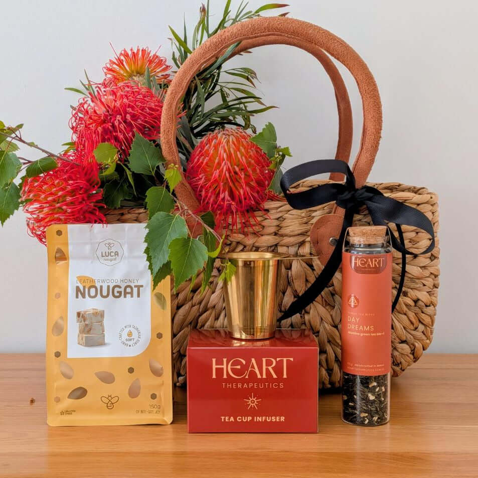 All Heart Gift Basket featuring nougat, tea cup infuser, and beautiful floral arrangement in a woven market basket.
