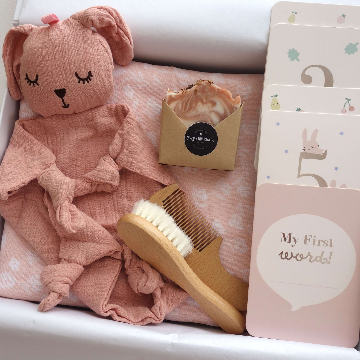 Perfectly Pink Baby Girl gift set featuring muslin wrap, bunny comforter, brush, handmade soap, and milestone cards.