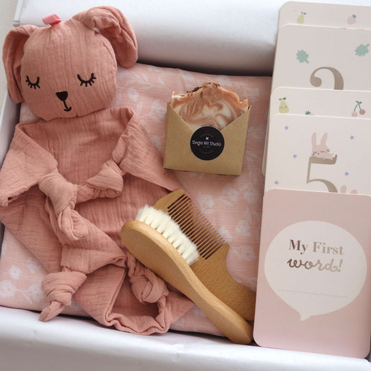 Perfectly Pink Baby Girl gift set featuring muslin wrap, bunny comforter, brush, handmade soap, and milestone cards.