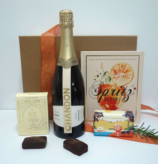 Summer celebration gift box featuring champagne, chocolates, and cocktail recipe book.
