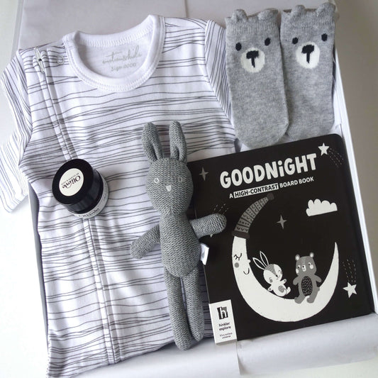 Welcome to the world baby gift hamper featuring a striped suit, bunny toy, board book, and socks.