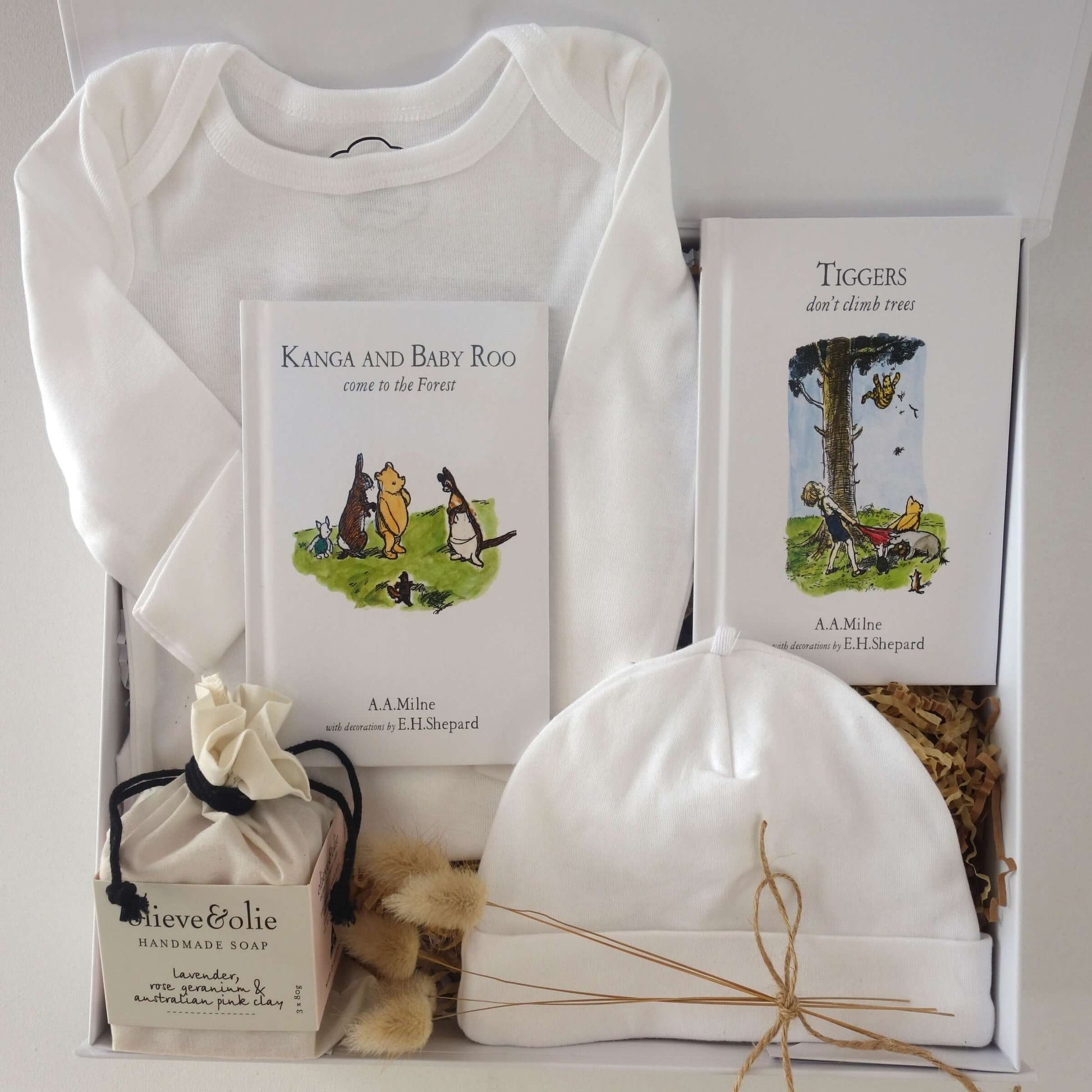 Baby gift box with white organic bodysuit, beanie, and Winnie the Pooh story books.
