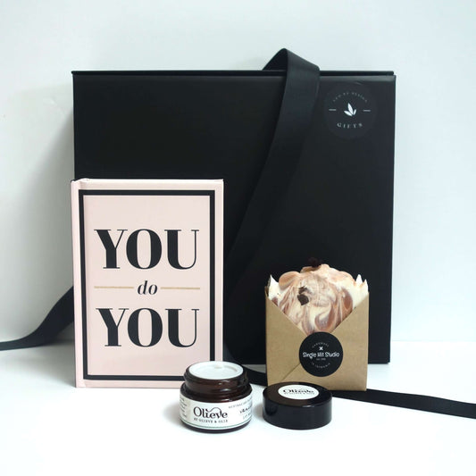 female self care gift box featuring a motivational book and skincare products.
