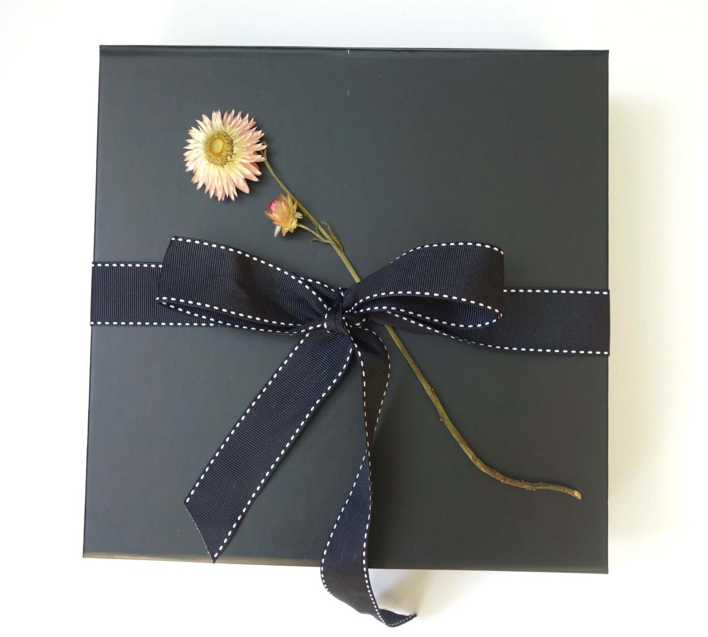 Indulgence black gift box with a floral decoration and navy ribbon for a luxury pampering experience.