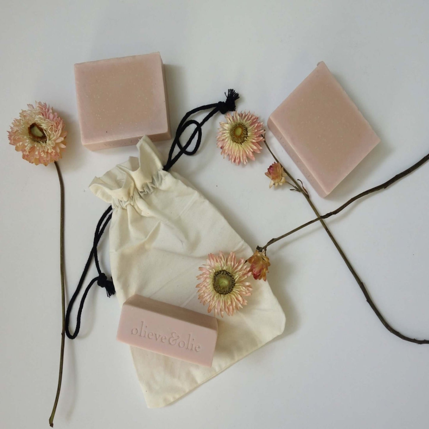 Indulgence gift box featuring handmade pink soap bars, elegant flowers, and a natural fabric pouch for pampering.