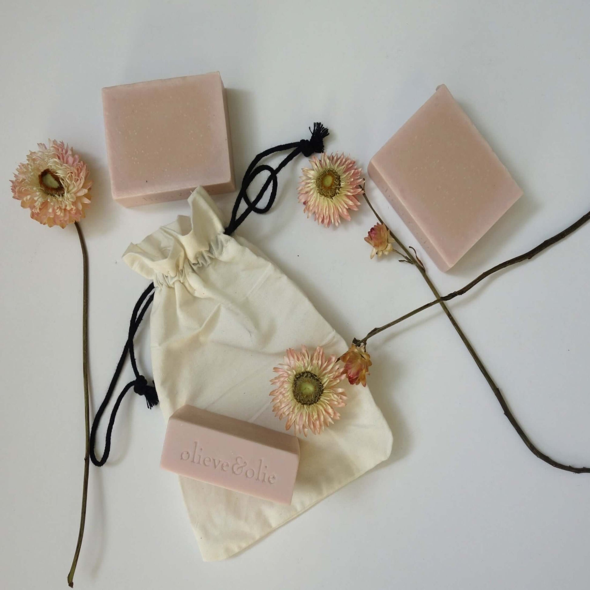 Indulgence gift box featuring handmade pink soap bars, elegant flowers, and a natural fabric pouch for pampering.