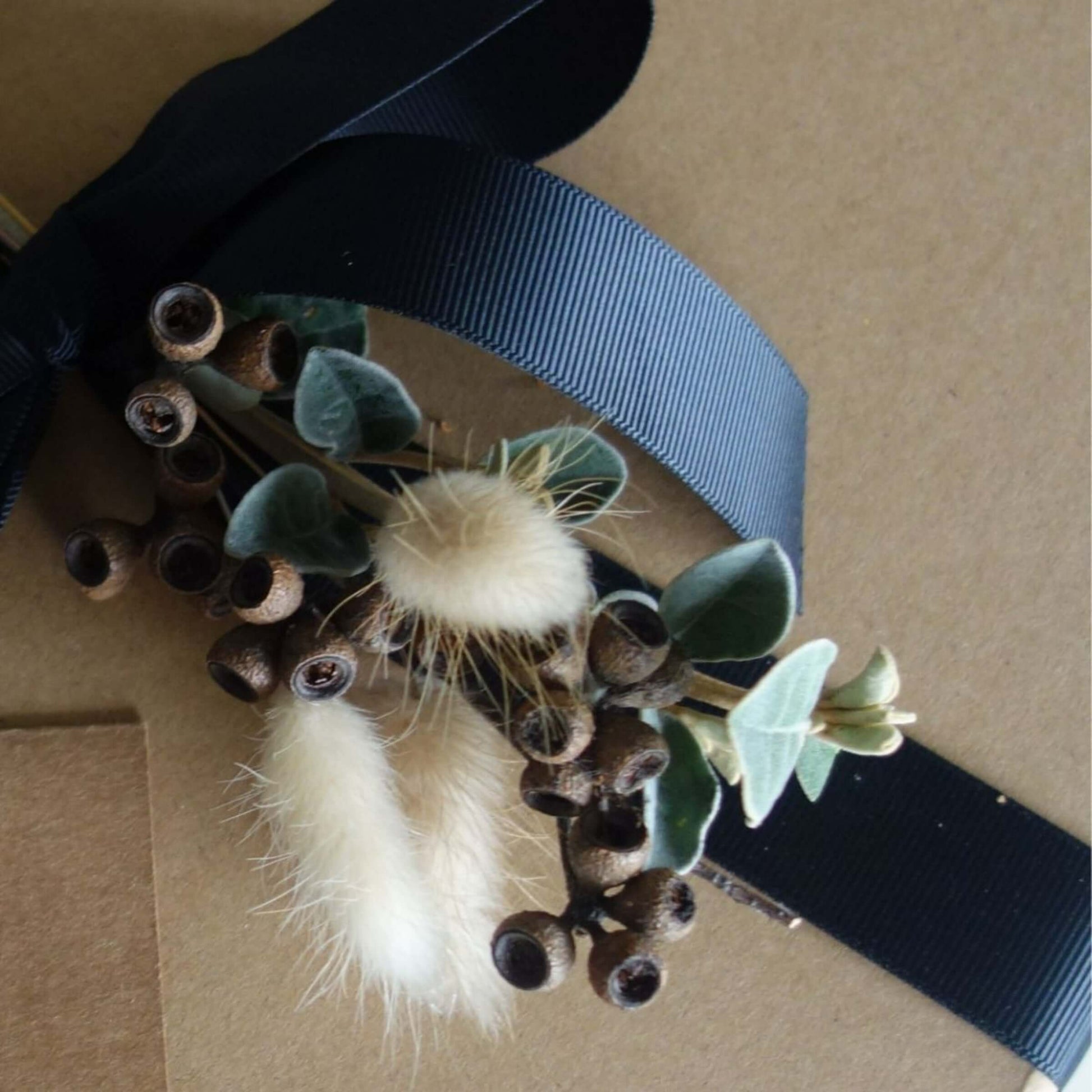 A gift of kindness featuring a bouquet of dried flowers and greenery tied with a black ribbon.